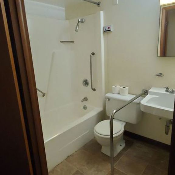 a white toilet with a roll of toilet paper on the side of a white sink.