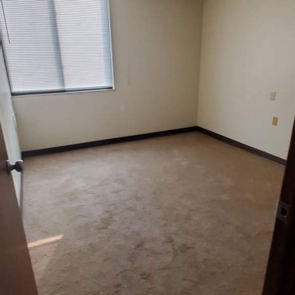 a room with a window and carpeted floor.