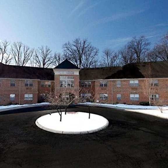a courtyard with a tree in the middle and a building in the background.