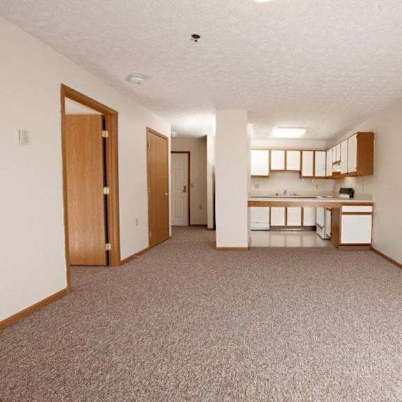 a sparsely furnished apartment with a kitchen area.