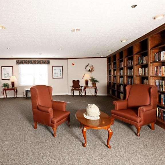 a living room with a carpeted floor and a bookshelf filled with books.