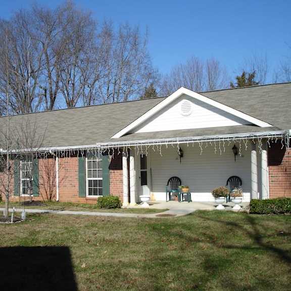 a white house with a porch and green shutters.