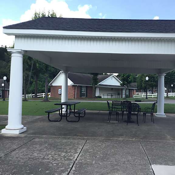 a white pavilion with a black roof is surrounded by four white columns.