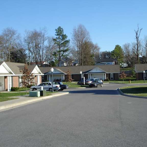 a residential street with houses on both sides and cars parked on the side.