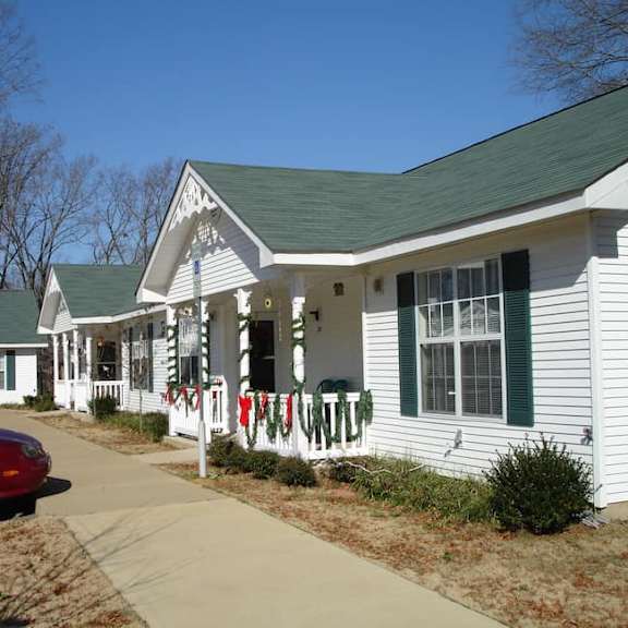 a white house with a green roof and a red car parked in front.