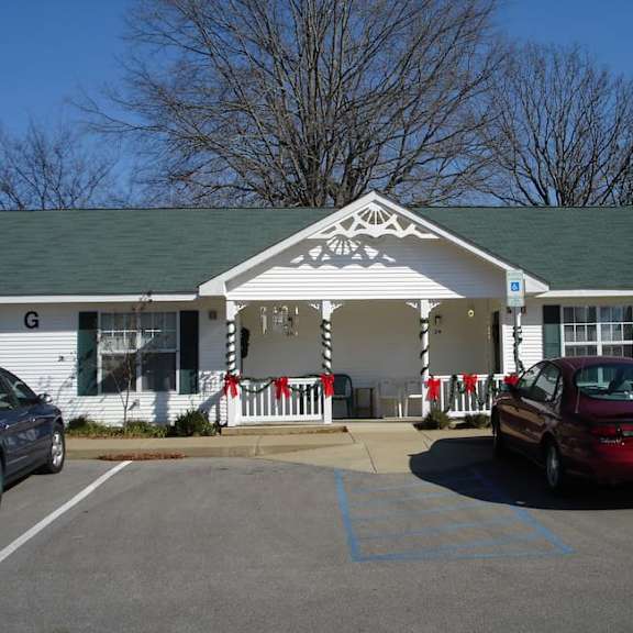 a white building with a green roof and a red car parked in front.