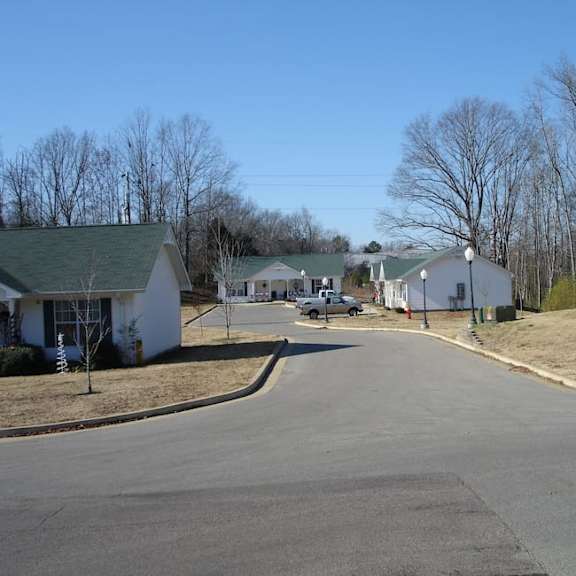 a white house with a green roof is surrounded by bare trees.