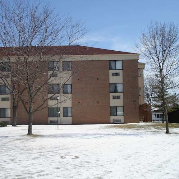 a large brick building with a brown roof and a parking lot in front.