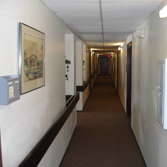 a long hallway with a brown carpet and white walls.