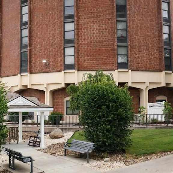 a tall red brick building with a white roof and a small gazebo in front of it.