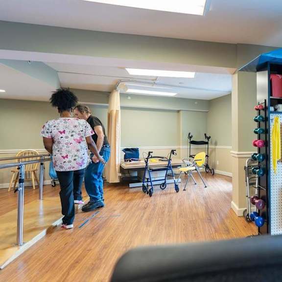 a woman and a man are standing in a room with a treadmill and a row of exercise equipment.