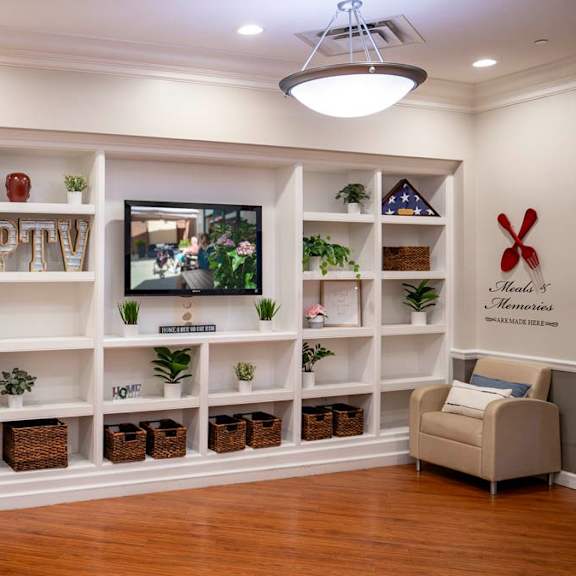 a living room with a white shelf, a clock, and a couch.
