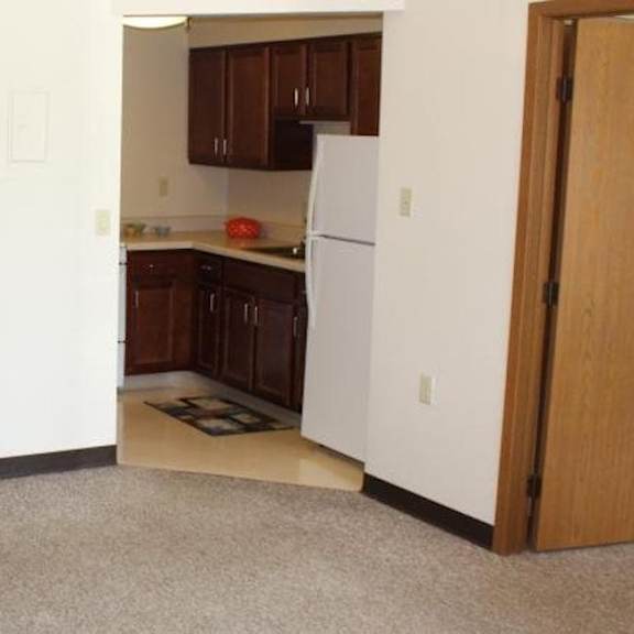 a kitchen with a white refrigerator and brown cabinets.