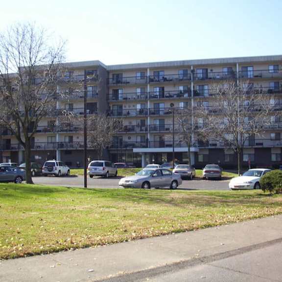 a large apartment building with a flag on top and cars parked in front.