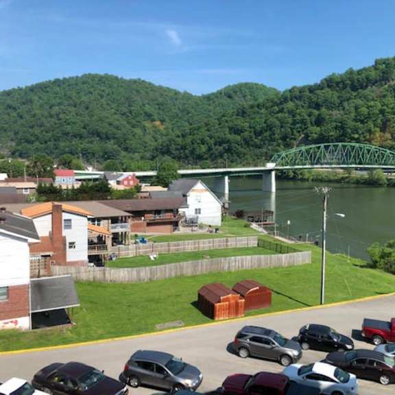 a parking lot with cars and a bridge over a river in the background.