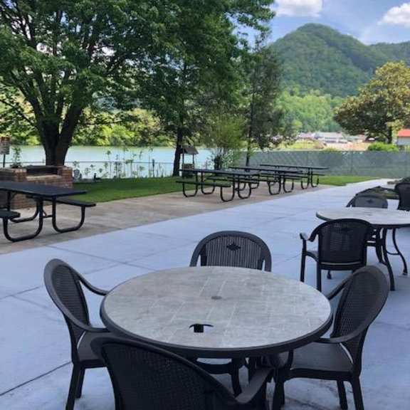a patio with tables and chairs overlooking a lake.