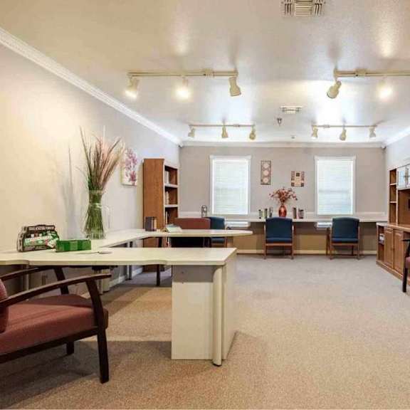 a room with a desk, chairs, and bookshelves.