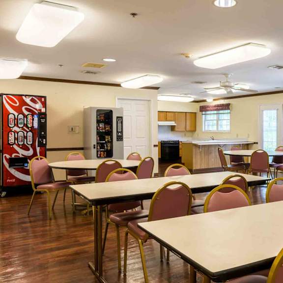 a room with tables and chairs and a soda machine.