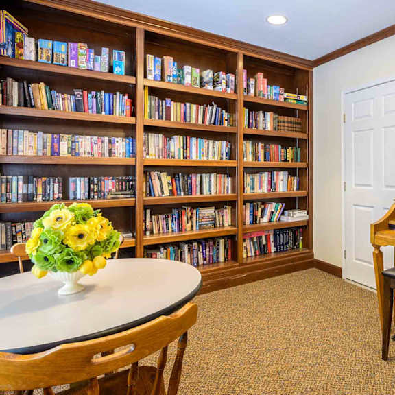 a room with a piano and a bookshelf filled with books.