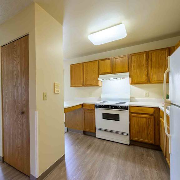 a kitchen with a white fridge, white stove and wooden cabinets.