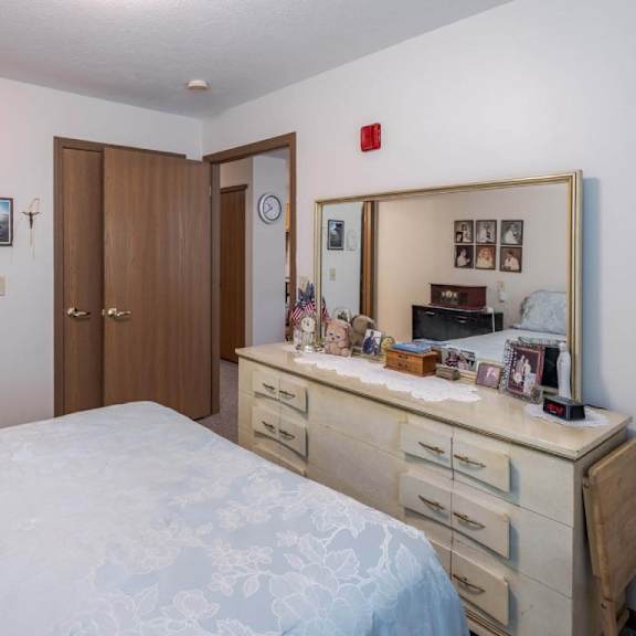 a bedroom with a bed, dresser, and mirror.