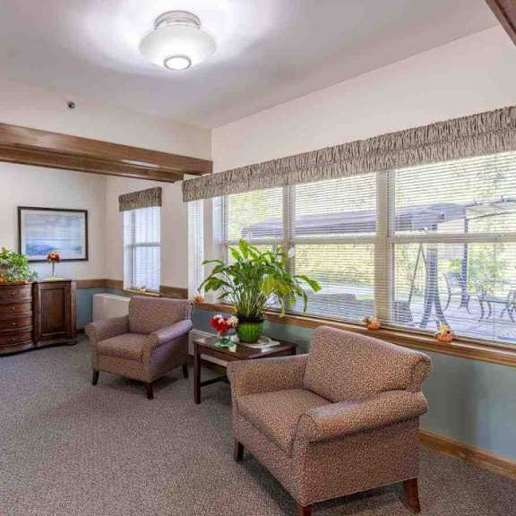 a living room with a sofa, armchair, and a table with a potted plant on it.