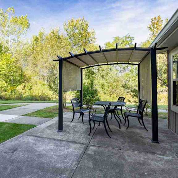 a patio with a table and chairs under a pergola.
