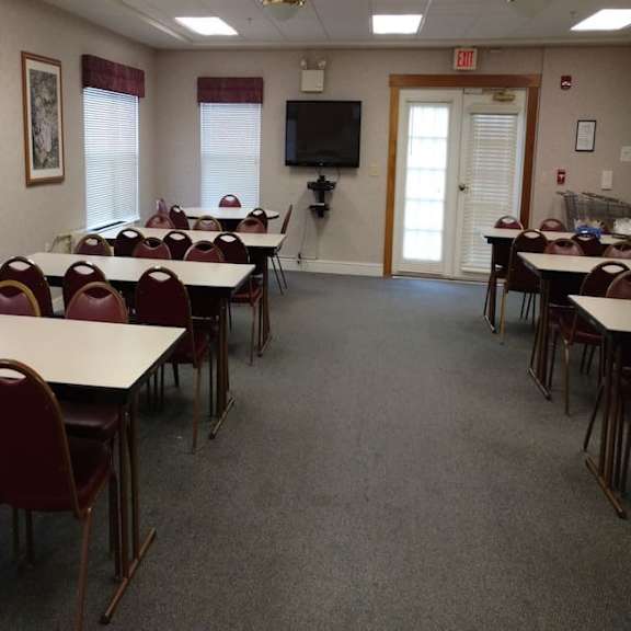 a room with tables and chairs and a tv on the wall.
