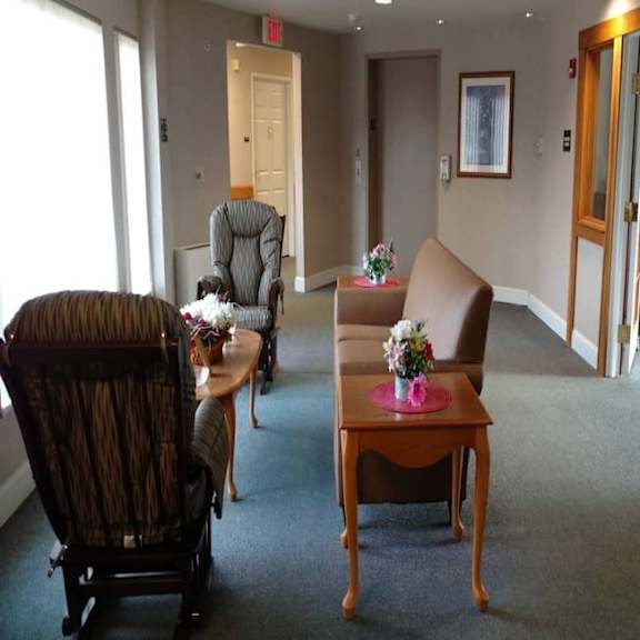 a room with a chair, a table, and a painting on the wall.