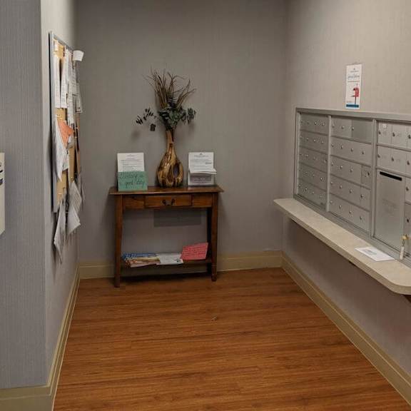a room with a mailbox and a vase with plants on a table.