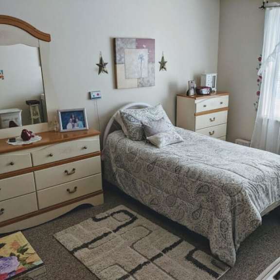 a bedroom with a bed, dresser, and mirror.