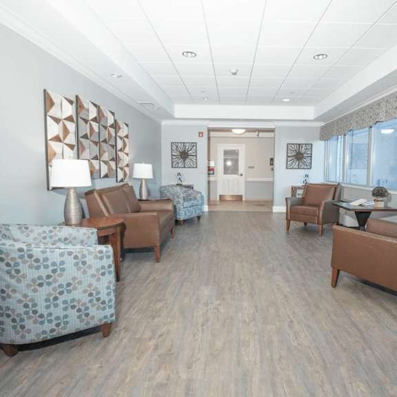 a waiting room with brown chairs and a patterned sofa.