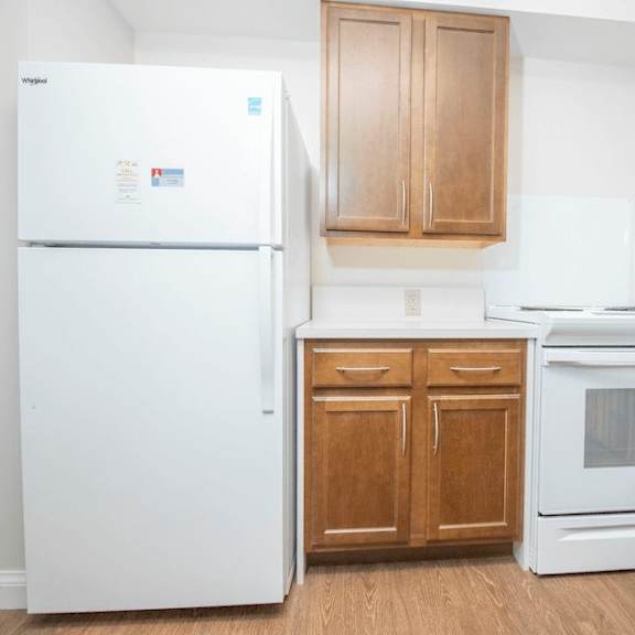 a white fridge and oven in a kitchen with wooden cabinets.