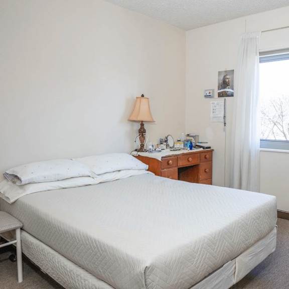 a bedroom with a large bed and a nightstand with a lamp.