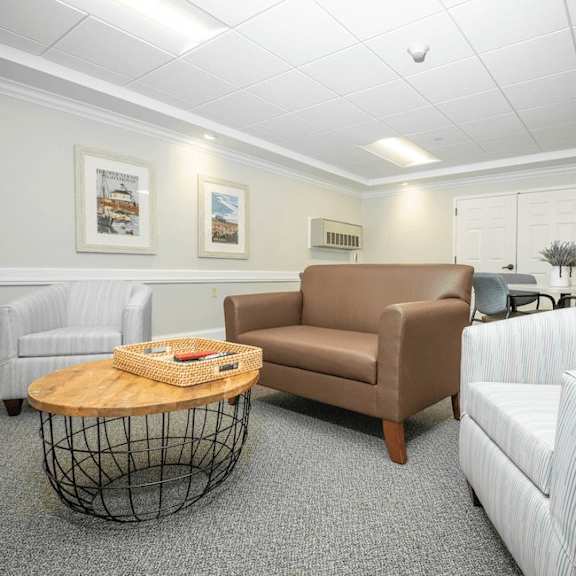 a waiting room with a brown couch, a white chair, and a wooden coffee table.