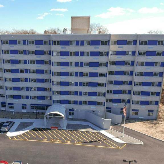 a parking lot in front of a large building with a no parking zone.