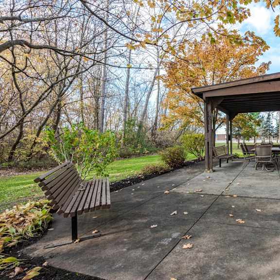 a patio with a bench and a table under a roof.