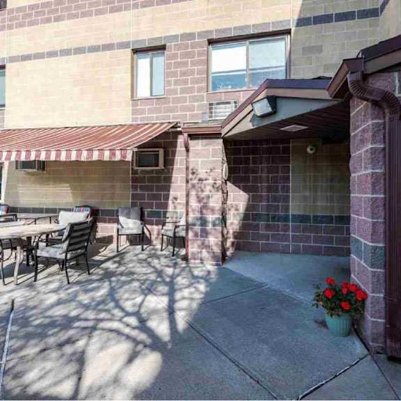 a patio with a table and chairs is in front of a brick building.