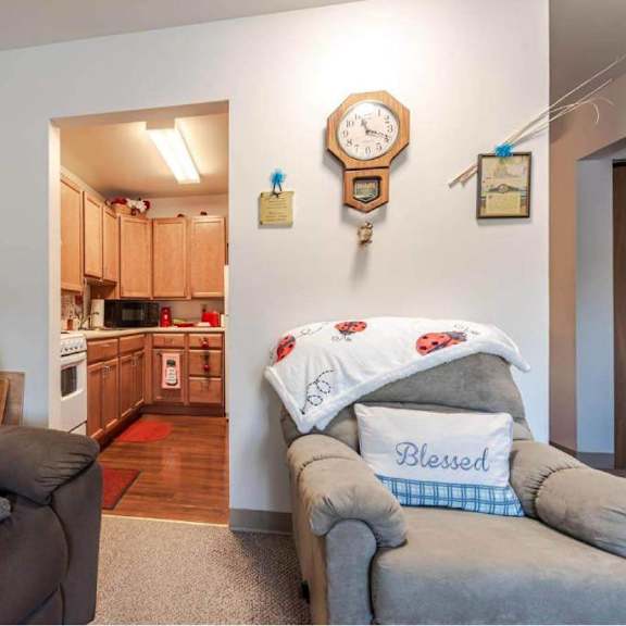 a living room with a brown recliner and a grey couch with a pillow that says "blessed".