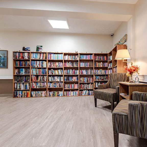 a room with a large bookshelf filled with books and two chairs.