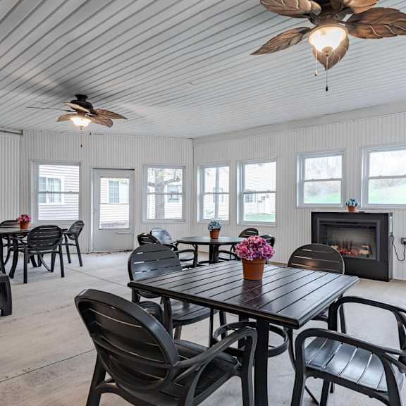 a black table with chairs is in a white room with a fireplace.