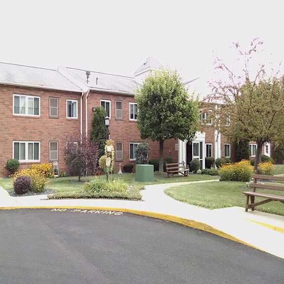 a street view of a residential area with a brick building, a bench, and a yellow line on the road.