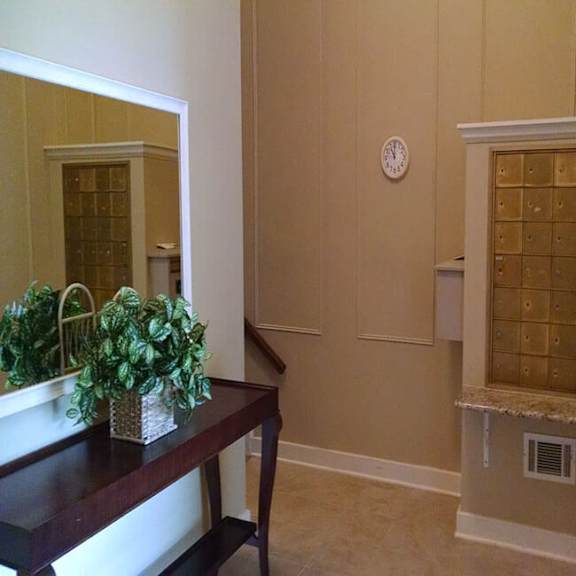a room with a plant on a table and a clock on the wall.
