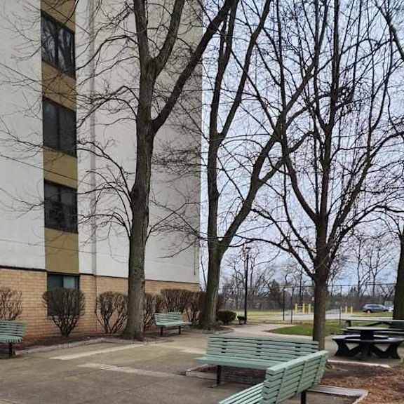 a green bench sits in a courtyard with a building in the background.