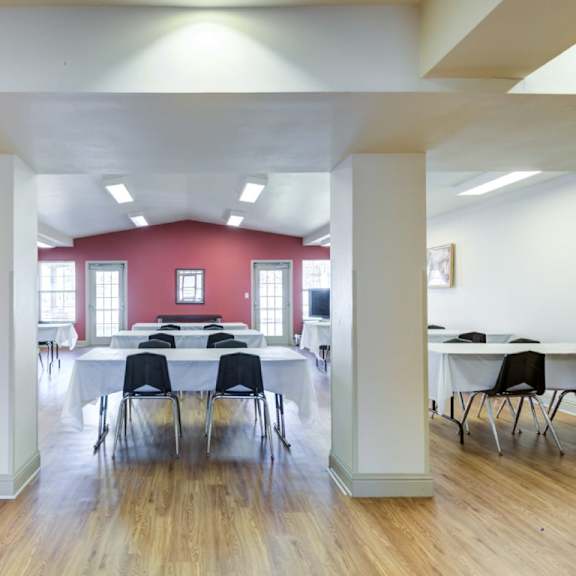 a room with tables and chairs and a red wall.