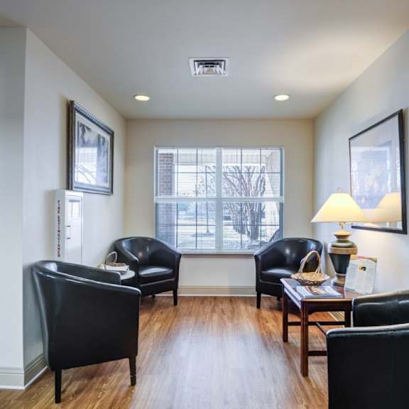 a living room with black leather chairs and a wooden table.