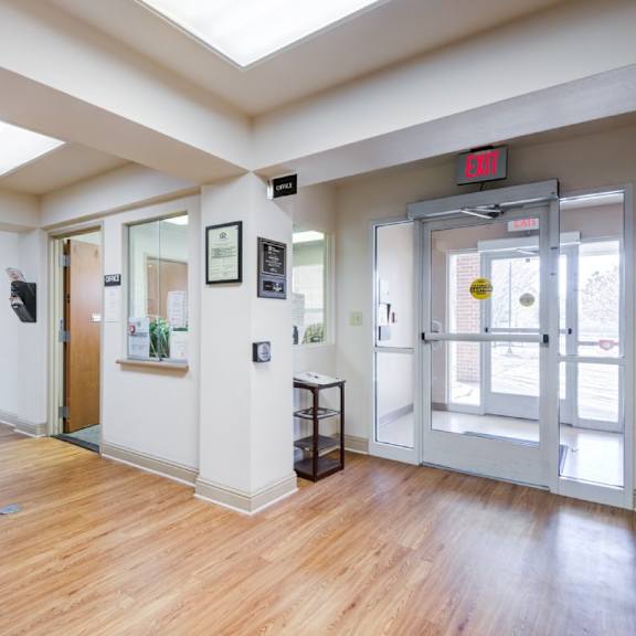 a hallway with a red exit sign above the door.
