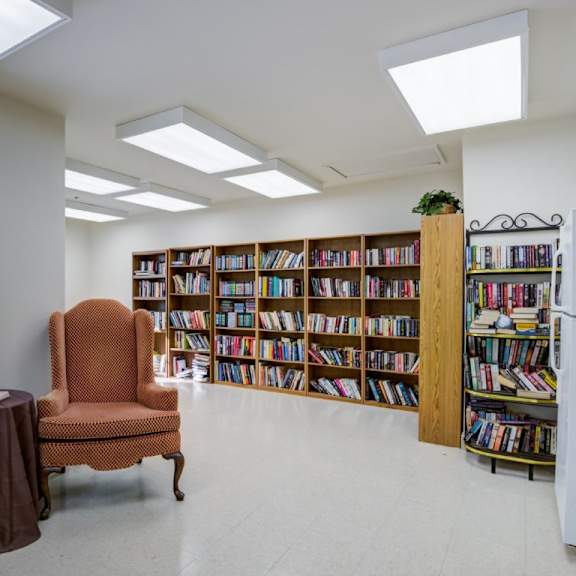 a room with a chair, a table, and a bookshelf.