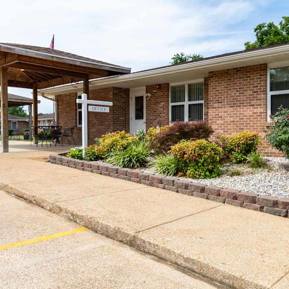 a small brick building with a porch and a sign that says "office" on it.