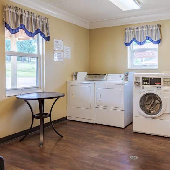 a laundry room with a washer and dryer, a table, and a bench.